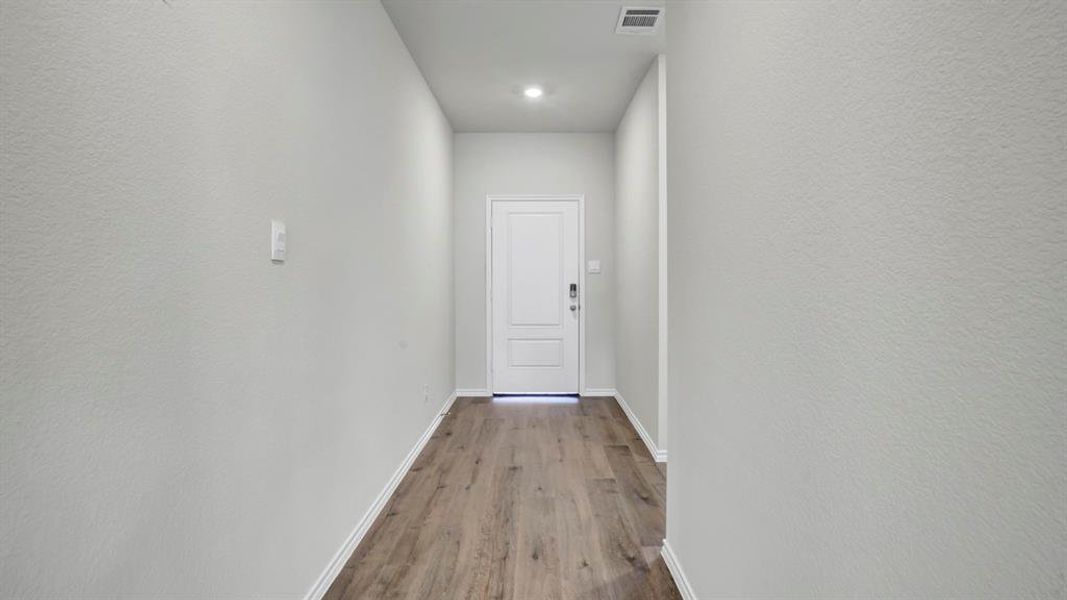 Doorway featuring wood finished floors, recessed lighting, and a textured wall