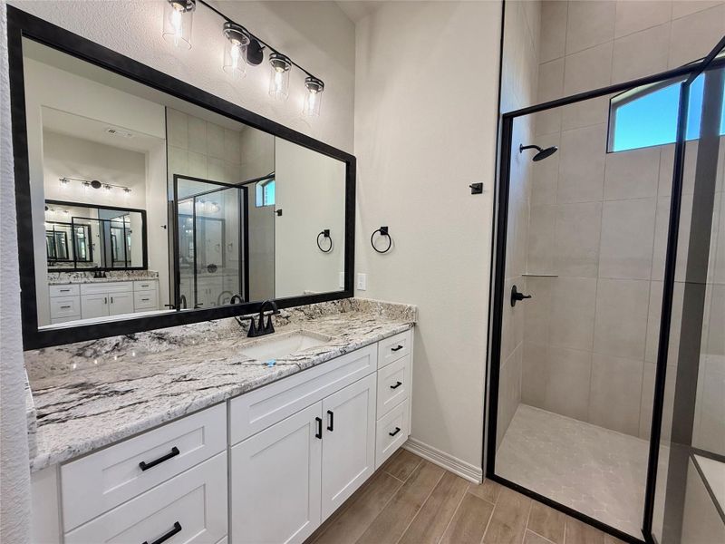 Full bath featuring a stall shower, vanity, and wood tiled floors