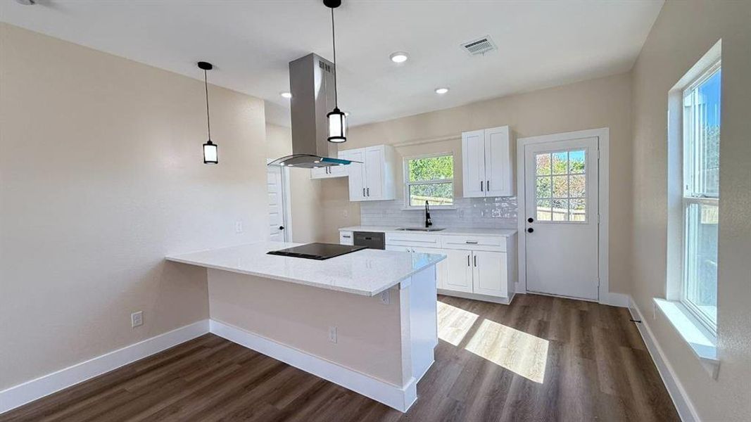 Kitchen with white cabinets, island exhaust hood, light stone counters, dark wood-style flooring, and recessed lighting