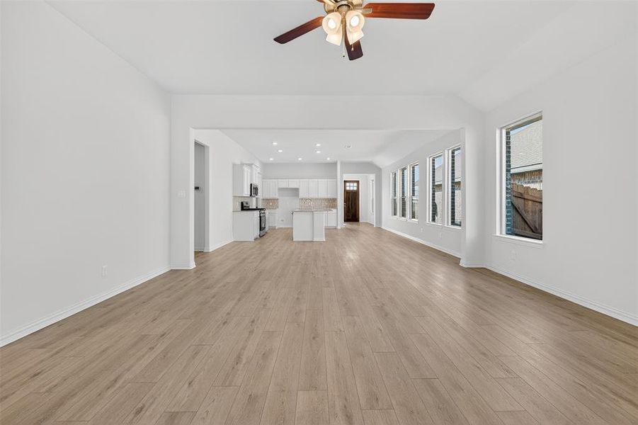 Unfurnished living room with light wood-style floors, recessed lighting, a ceiling fan, and lofted ceiling