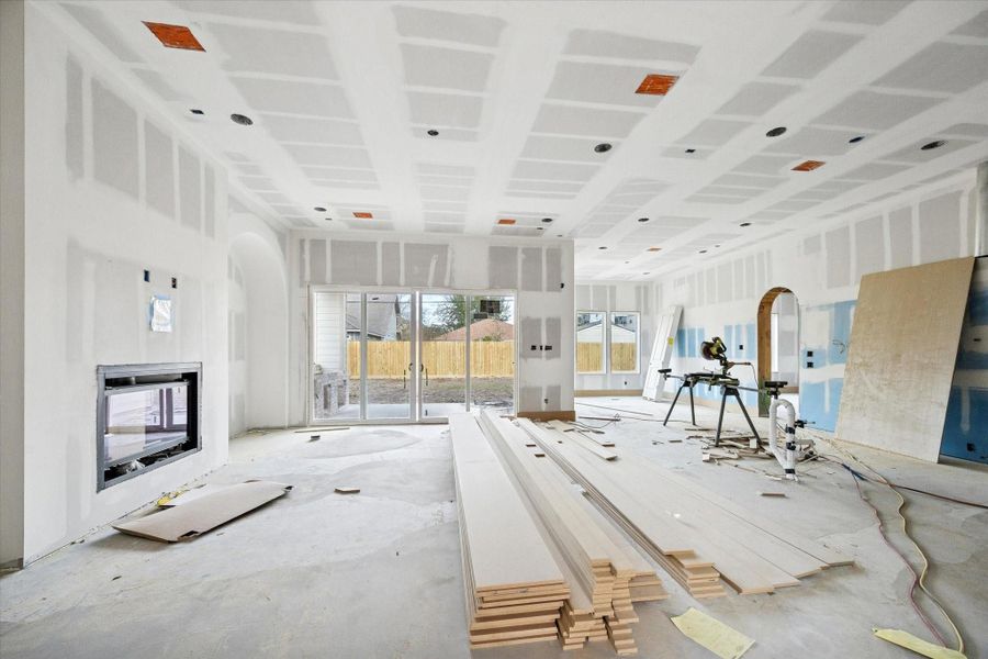 The primary living area showcases impressive ceiling height and an open layout anchored by a statement fireplace with built-in's on either side.