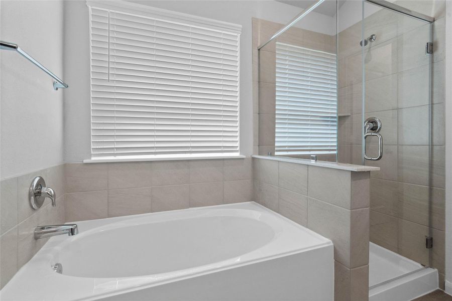 Indulge in relaxation within this spa-inspired primary bathroom, offering both a quick shower and a tranquil soaking experience. The walk-in shower is glass enclosed with modern tile walls and sleek finishes.