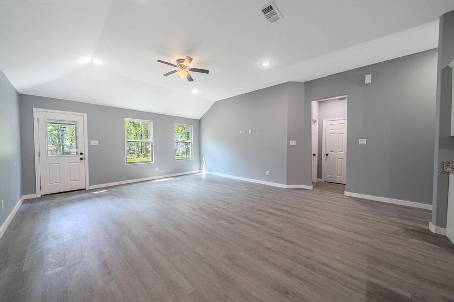 Unfurnished living room featuring dark wood-style flooring, ceiling fan, vaulted ceiling, and recessed lighting Unfurnished living room featuring dark wood-style flooring, ceiling fan, vaulted ceiling, and recessed lighting