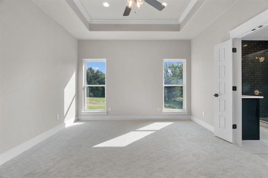 Empty room with light carpet, ornamental molding, a tray ceiling, ceiling fan, and recessed lighting