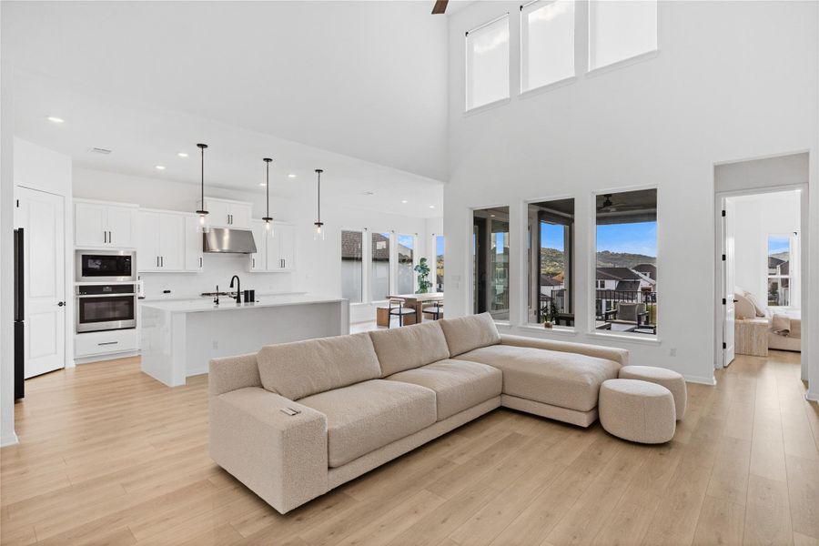 Living room featuring light wood-style floors, recessed lighting, and a high ceiling