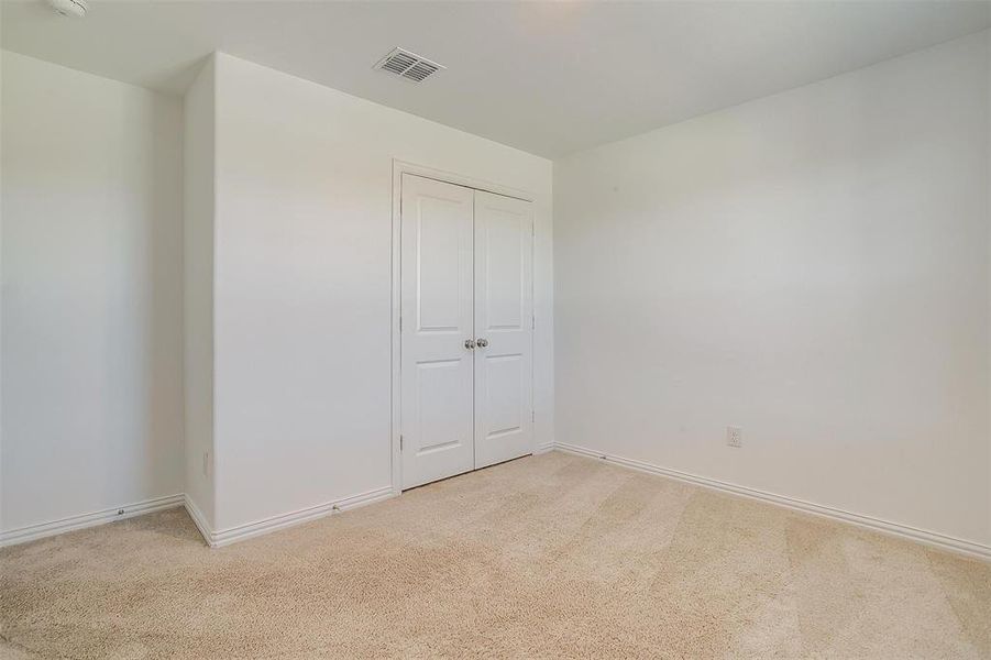 Unfurnished bedroom featuring light carpet and a closet