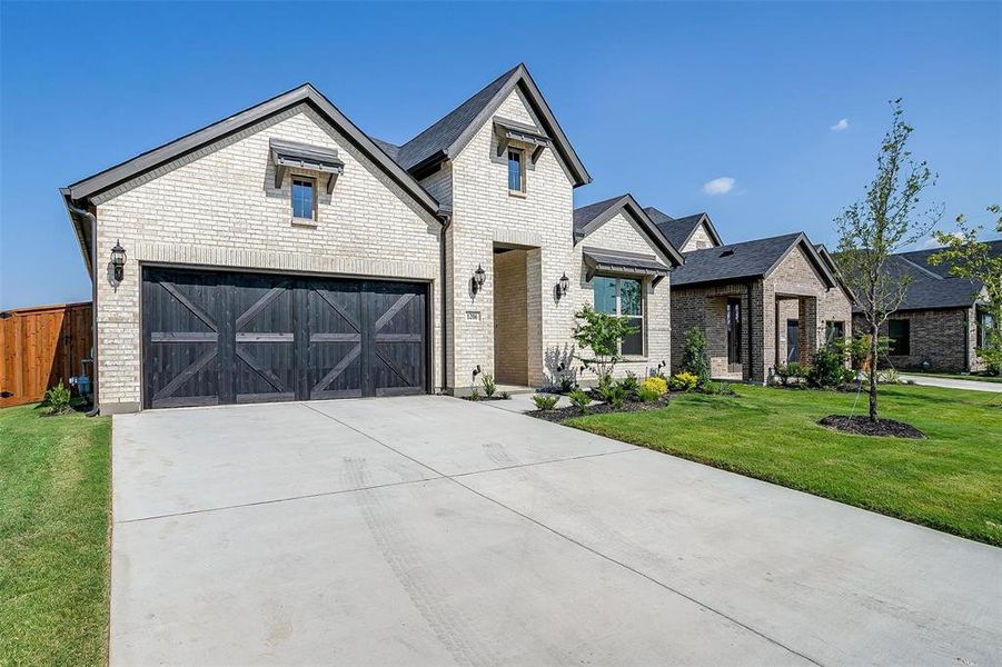 View of front facade featuring a front yard and a garage