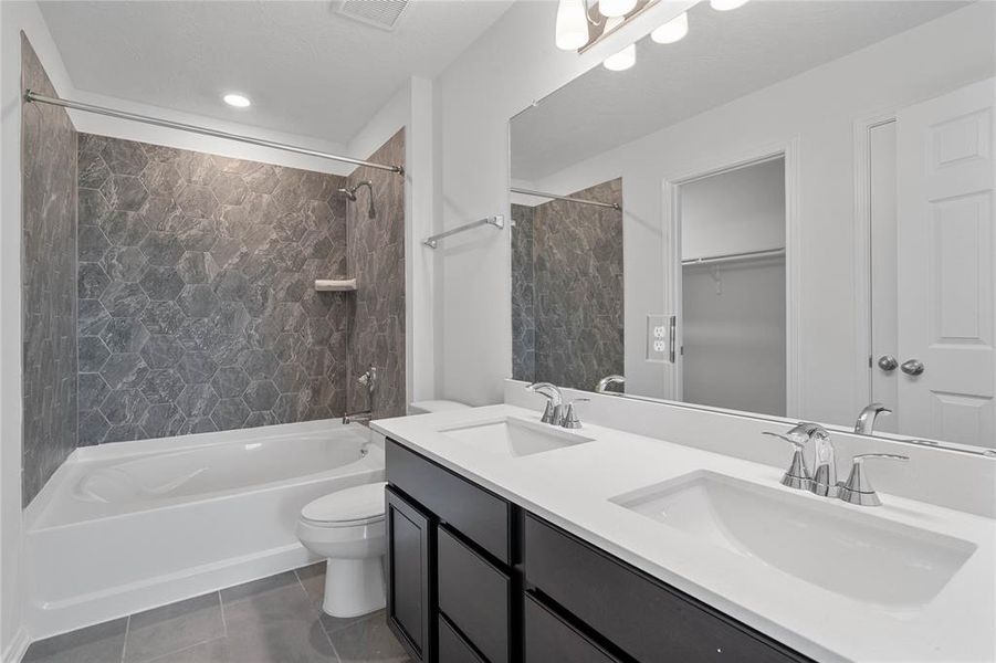 This primary bathroom is definitely move-in ready! Featuring an oversized tub/shower combo with tile surround, stained cabinets with light countertops, spacious walk-in closet with shelving, high ceilings, neutral paint, sleek and modern finishes.