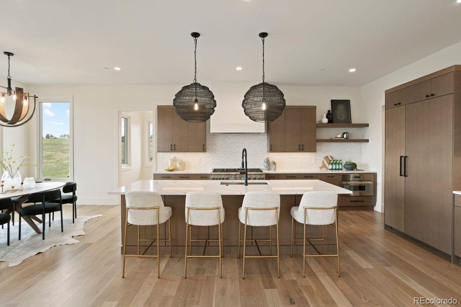 Gourmet kitchen showcases a sleek tile backsplash, warm wood floors, a spacious quartz island, and striking modern pendant lighting.
