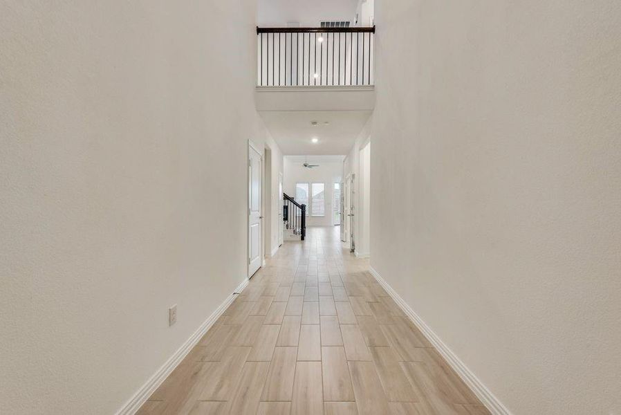 Hall featuring a high ceiling and light wood-type flooring