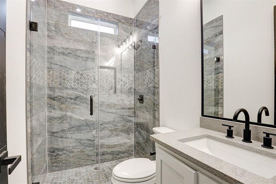 Bathroom with an enclosed shower, vanity, and toilet