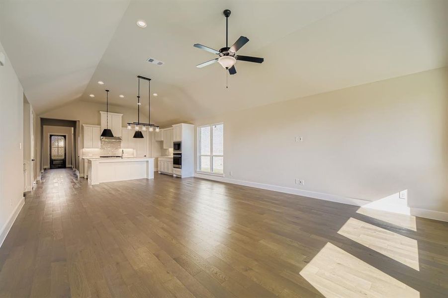 Unfurnished living room featuring light wood-type flooring, vaulted ceiling, recessed lighting, and a ceiling fan Unfurnished living room featuring light wood-type flooring, vaulted ceiling, recessed lighting, and a ceiling fan