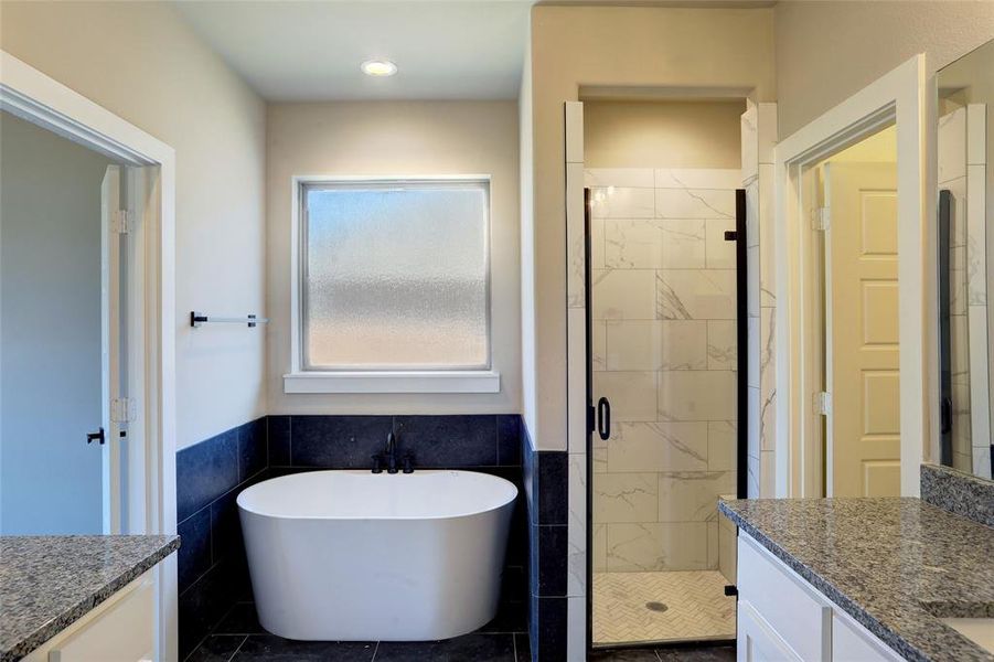Full bathroom with vanity, a soaking tub, a shower stall, tile walls, and a wainscoted wall Full bathroom with vanity, a soaking tub, a shower stall, tile walls, and a wainscoted wall