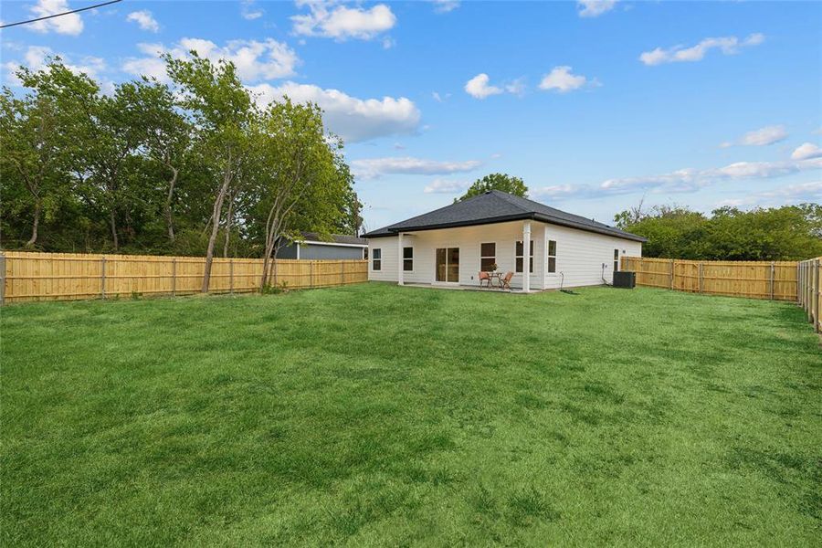 Huge fenced backyard featuring a patio