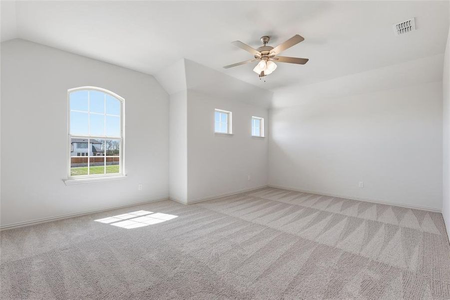 Spacious room featuring vaulted ceilings and neutral-toned patterned carpet