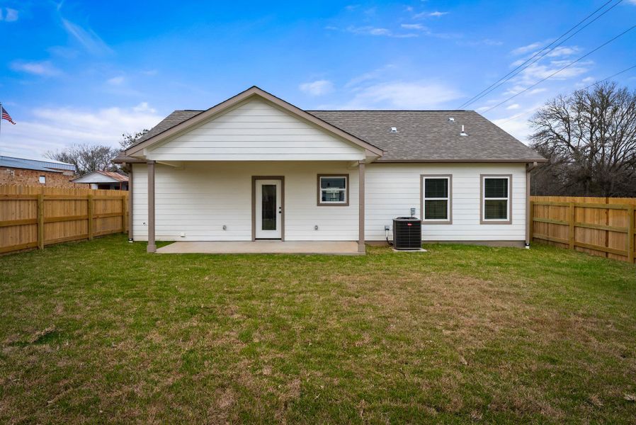 Back of property featuring a fenced backyard, a shingled roof, and a patio area