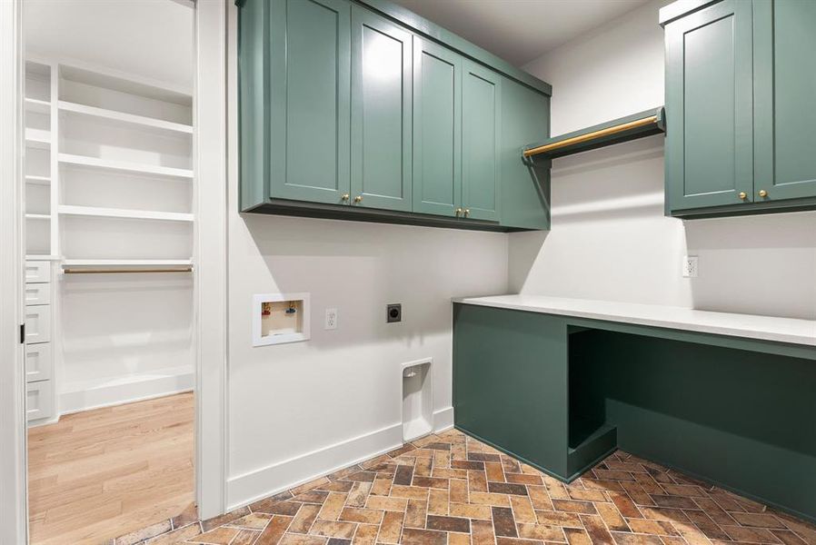 Laundry area with hookup for an electric dryer, hookup for a washing machine, brick patterned floors, and cabinet space