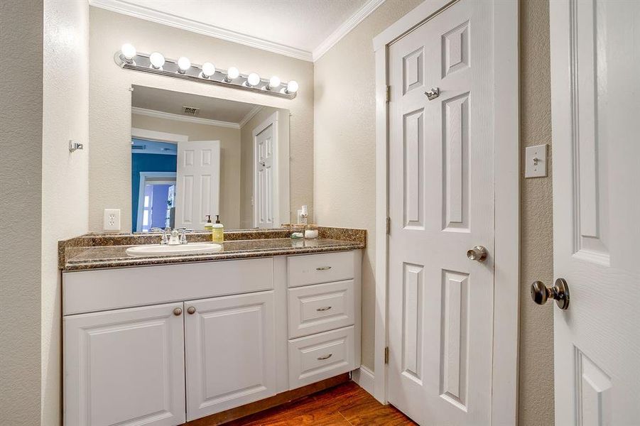 Bathroom with ornamental molding, vanity, a textured wall, and dark wood finished floors