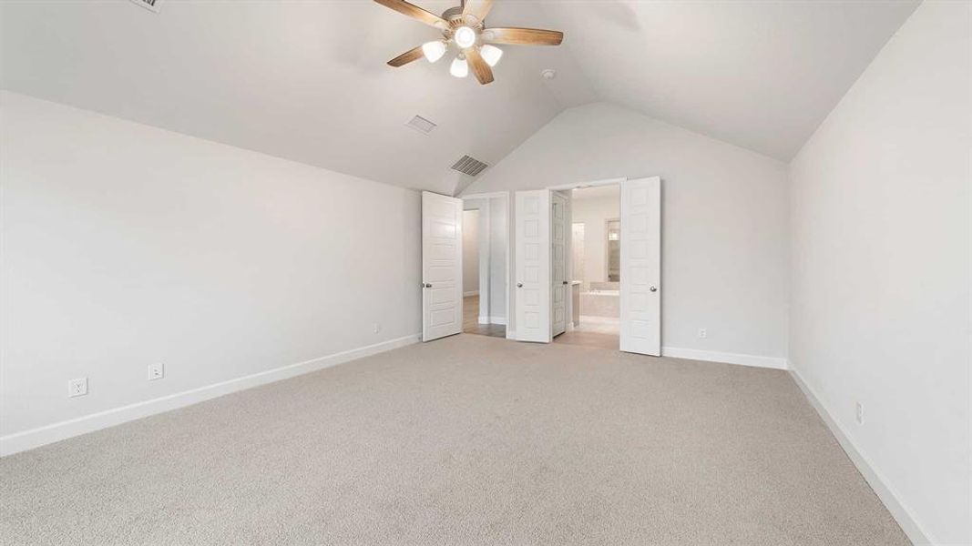 Unfurnished bedroom featuring lofted ceiling, ensuite bathroom, carpet floors, and ceiling fan