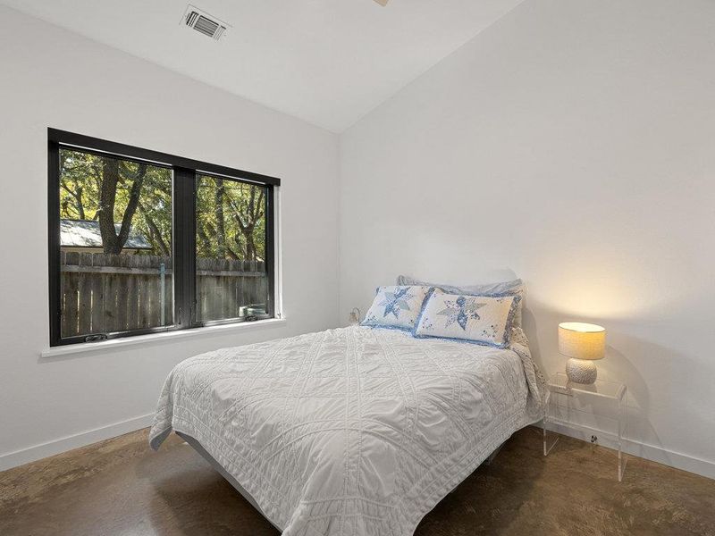 Bedroom featuring concrete floors and vaulted ceiling