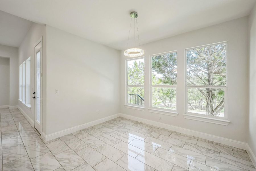 Unfurnished dining area with light marble finish floors and baseboards