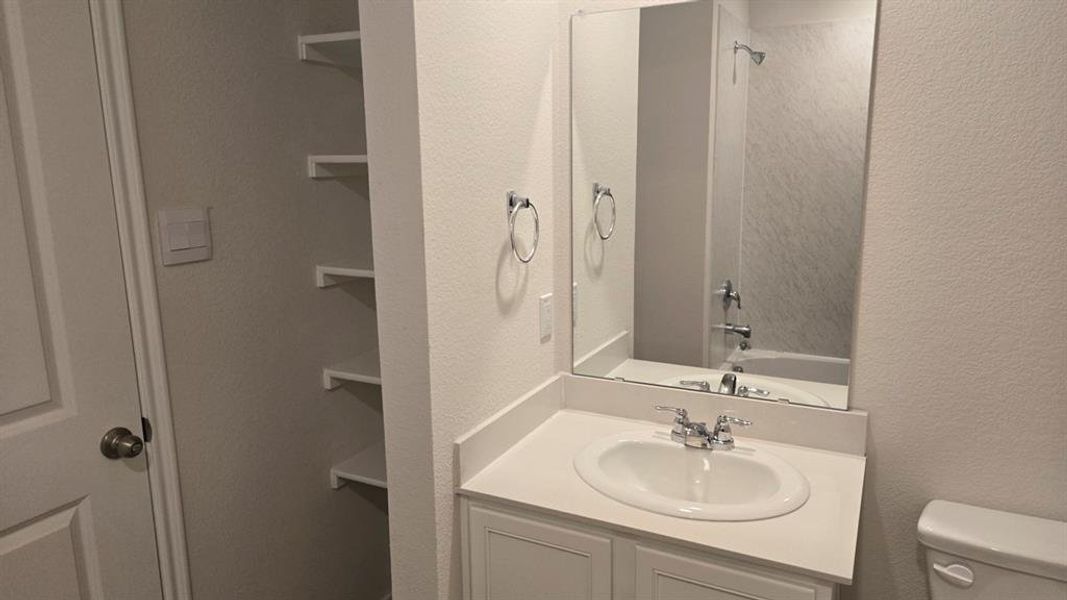 Bathroom featuring a textured wall, vanity, shower / washtub combination, and a closet