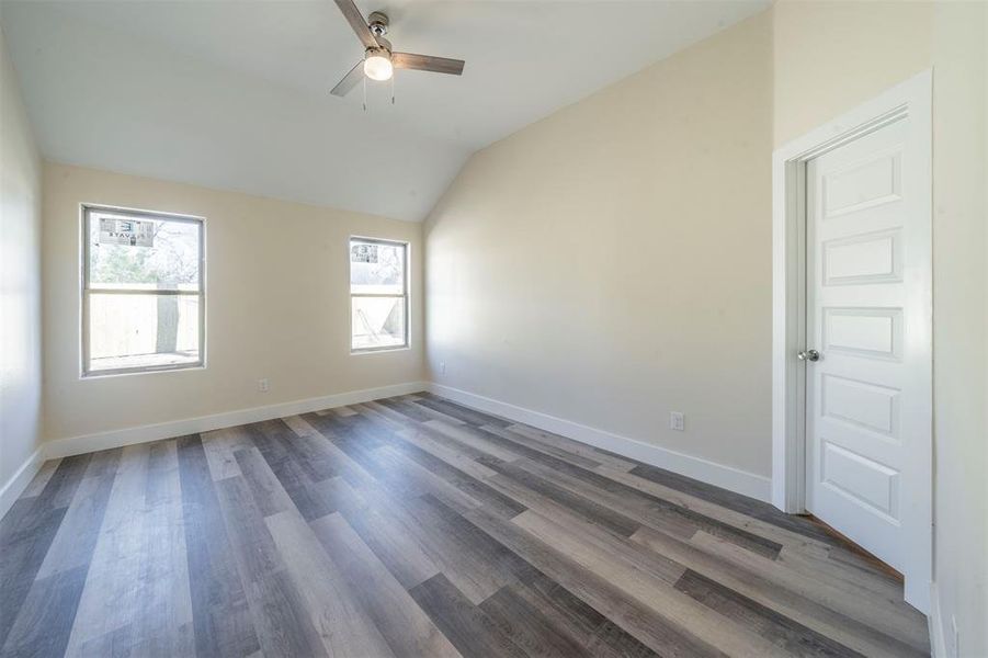 Unfurnished room with a ceiling fan, vaulted ceiling, baseboards, and wood finished floors