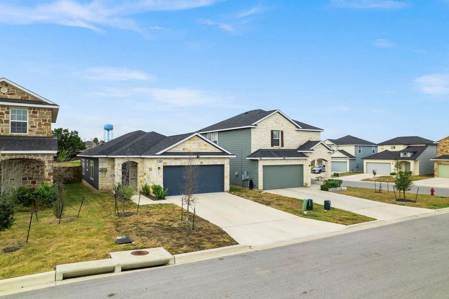 View of front of house featuring stone siding, driveway, a front yard, and a residential view