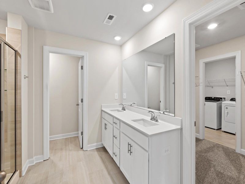 The modern primary bathroom offers a spa-like experience with convenient access to the laundry room. The modern primary bathroom offers a spa-like experience with convenient access to the laundry room.