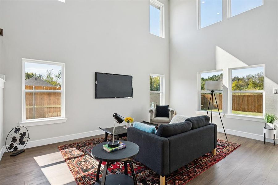 Living area with healthy amount of natural light, a high ceiling, and wood finished floors