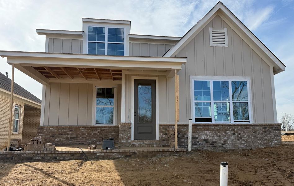 View of front of property with board and batten siding, brick siding, and covered porch