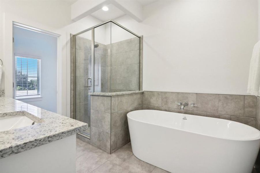 Bathroom featuring vanity, tile walls, and independent shower and bath