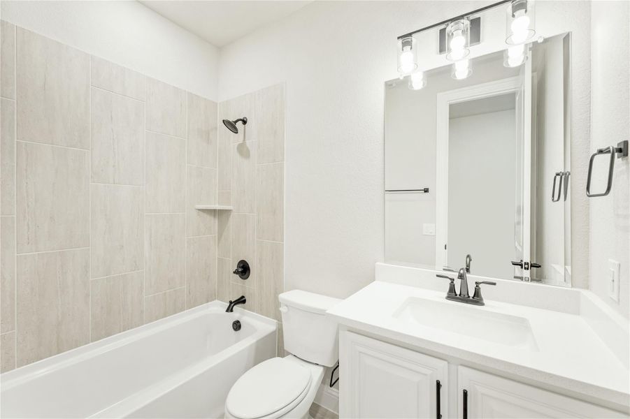 Full bathroom with tiled tub and shower, white vanity, and lighted mirror above sink Full bathroom with tiled tub and shower, white vanity, and lighted mirror above sink