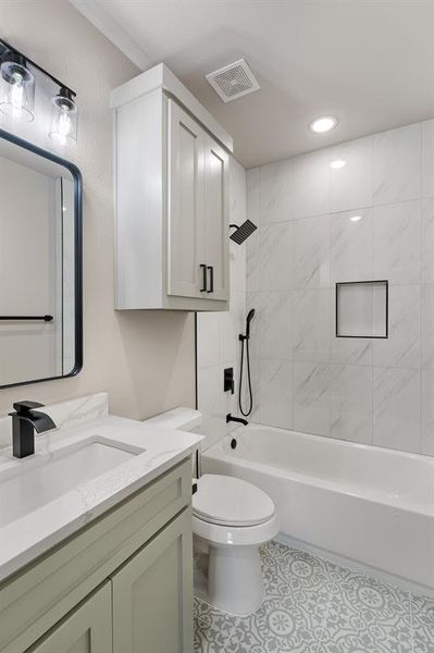 Full bathroom with tile flooring, tiled shower / bath combo, vanity, and toilet