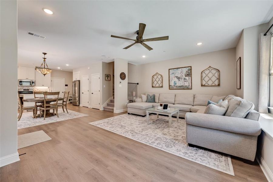 Living area with a ceiling fan, light wood finished floors, and a chandelier