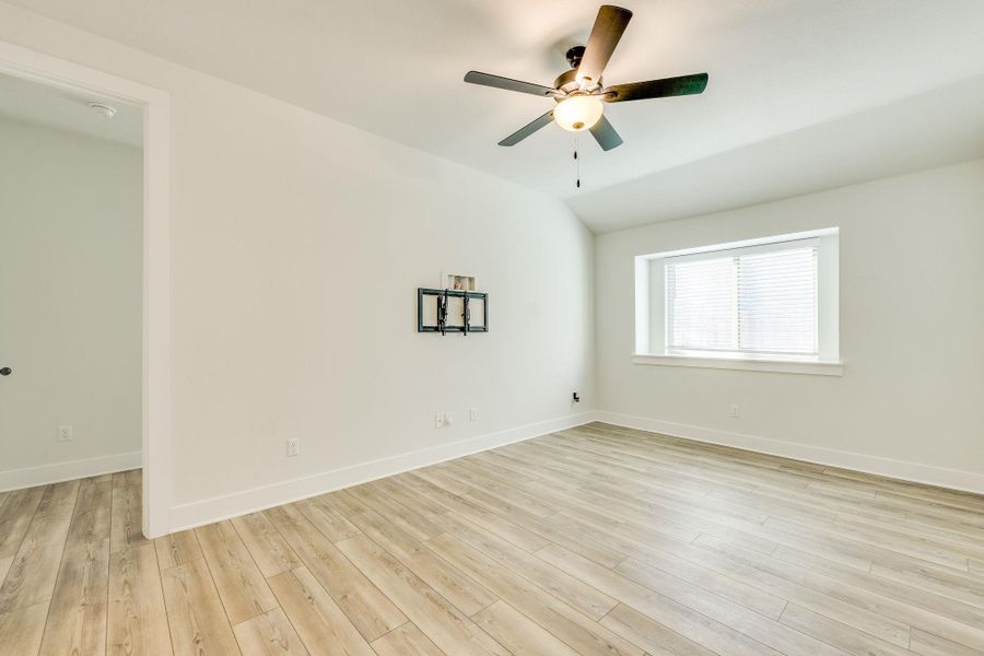 Unfurnished room with light wood finished floors, a ceiling fan, and lofted ceiling