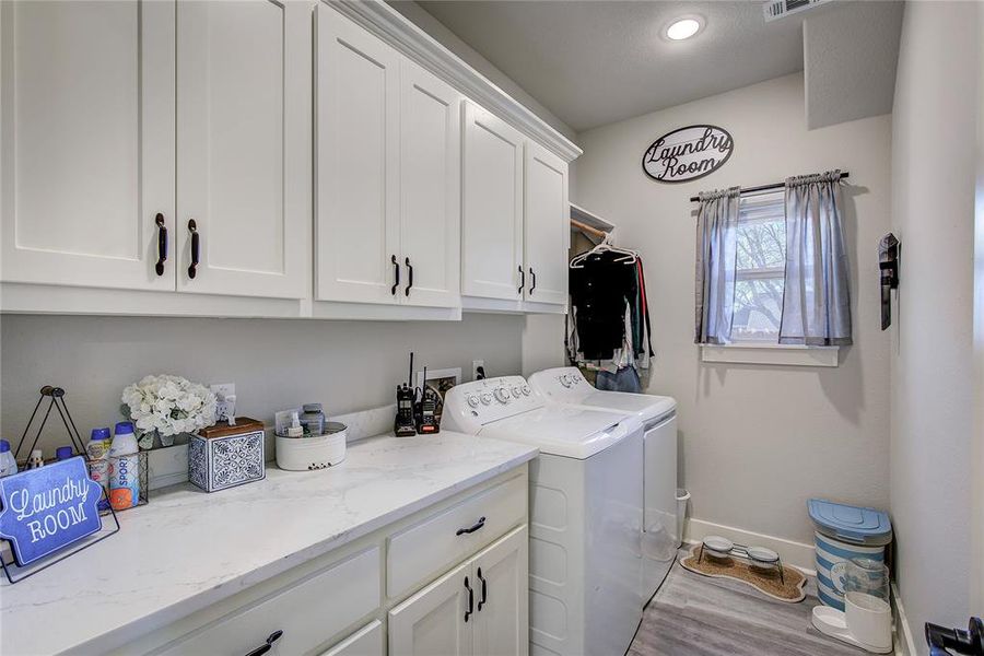 Clothes washing area featuring washer and clothes dryer, cabinets, and light hardwood / wood-style floors