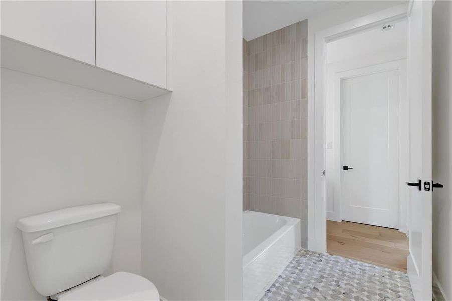 Full bath with toilet and wood finished floors Full bath with toilet and wood finished floors