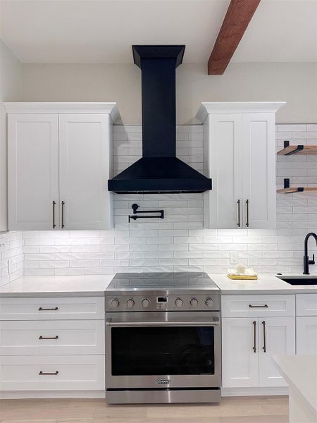 Kitchen featuring 36" Cosmo stainless steel range, white cabinetry, wall chimney range exhaust hood, boutique subway tile backsplash, and solid beams at ceiling