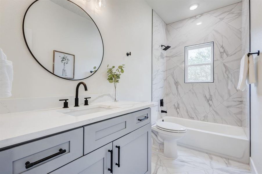 Full bathroom featuring tiled shower / bath, vanity, and toilet