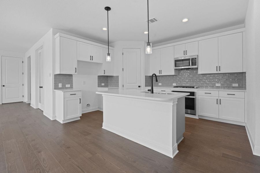 Kitchen with backsplash, hanging light fixtures, appliances with stainless steel finishes, white cabinetry, and dark wood-type flooring Kitchen with backsplash, hanging light fixtures, appliances with stainless steel finishes, white cabinetry, and dark wood-type flooring