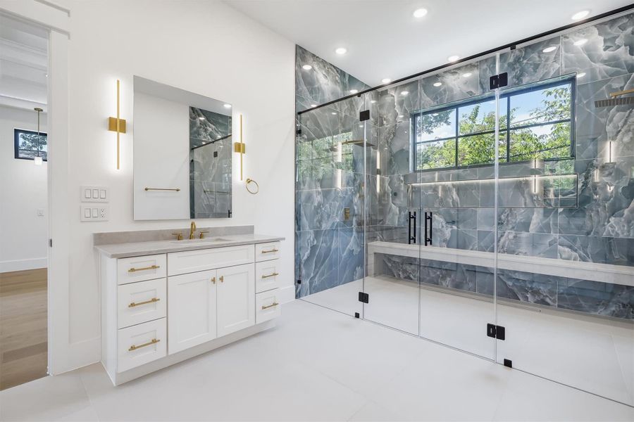 Two separate vanity spaces with natural stone countertops and backlit mirrors.