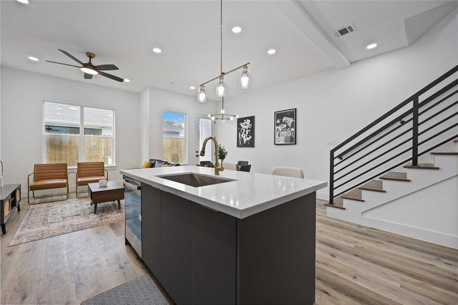 The island is open to the living and dining areas and features a sleek light fixture and quartz countertops. Gorgeous floors adorn this modern living space.