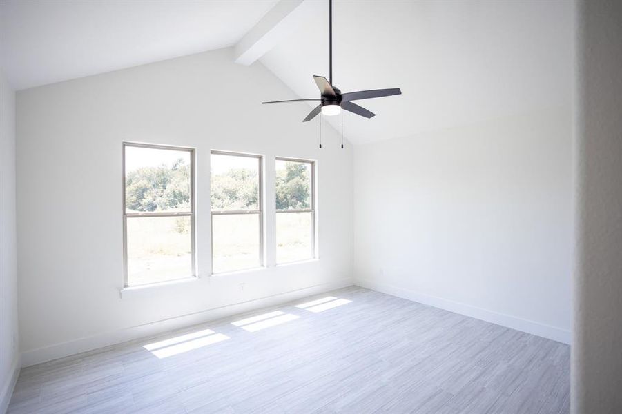 Unfurnished room featuring beam ceiling, light wood-type flooring, a ceiling fan, and high vaulted ceiling Unfurnished room featuring beam ceiling, light wood-type flooring, a ceiling fan, and high vaulted ceiling