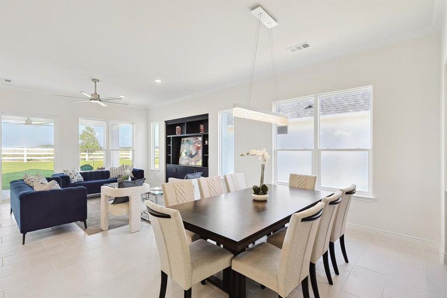 Dining space with ornamental molding, ceiling fan, and light tile floors