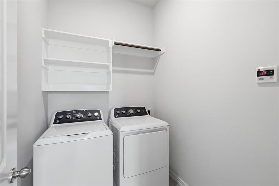 Dedicated laundry area featuring a white top-load washing machine, white front-load dryer, built-in shelving, and a hanging rod