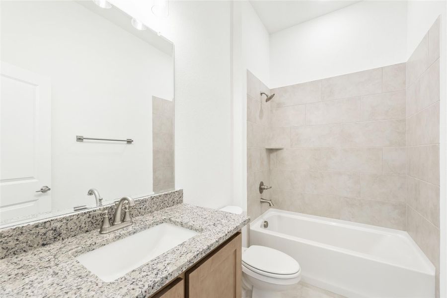 Bathroom with granite vanity, large mirror, and tiled shower-tub combo with brushed nickel fixtures Bathroom with granite vanity, large mirror, and tiled shower-tub combo with brushed nickel fixtures