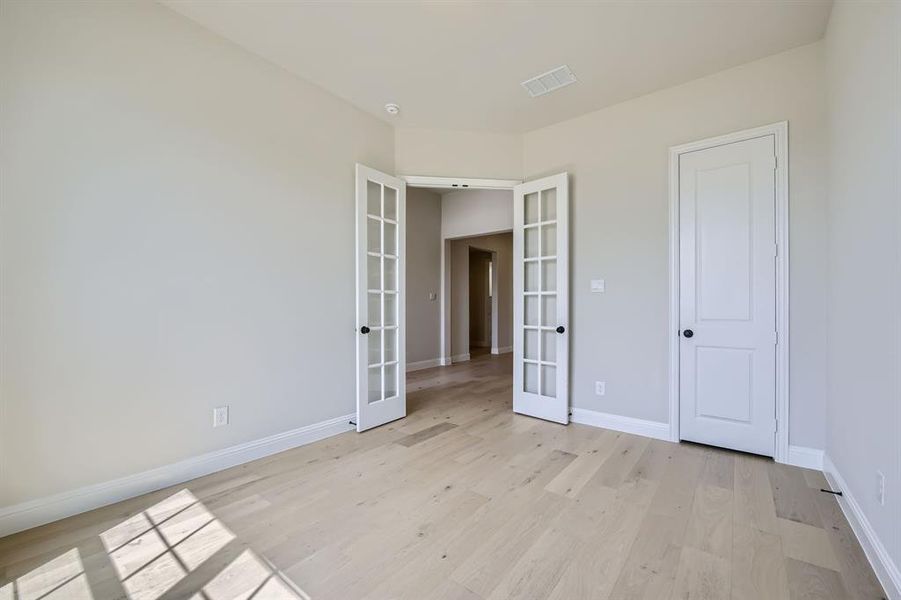 Unfurnished bedroom with light hardwood / wood-style flooring, a closet, and french doors