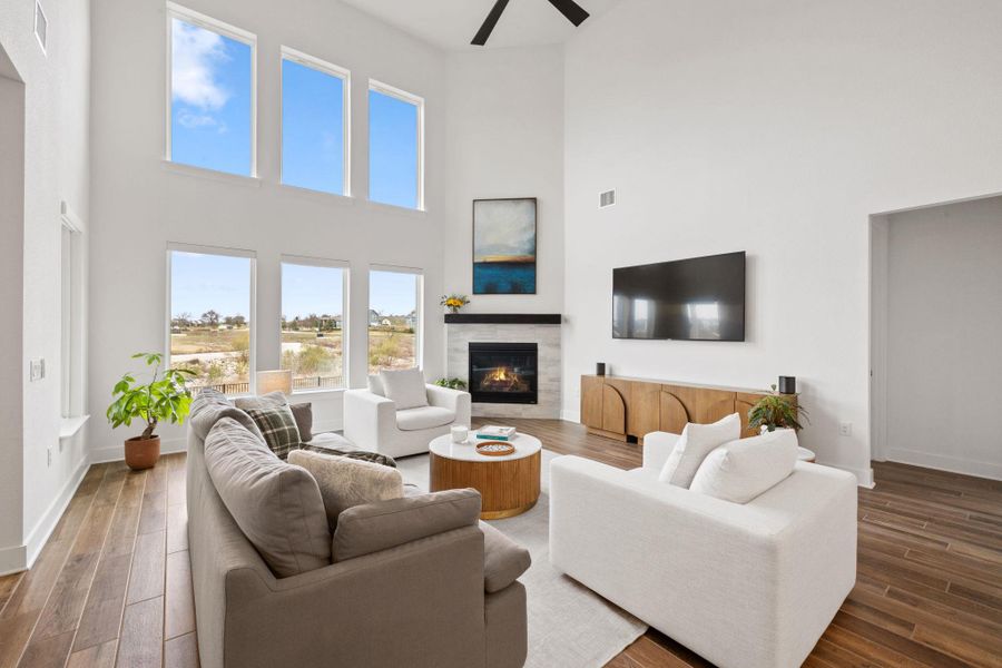 Living room with fireplace, ceiling fan, tiled finished floors, and a towering ceiling