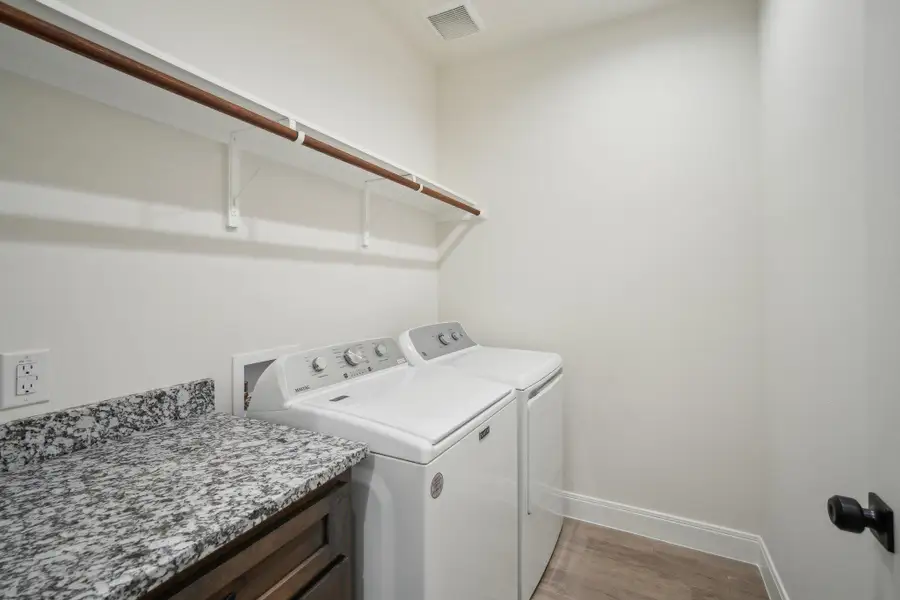 Clothes washing room featuring washing machine and dryer, wood finished floors, laundry area, baseboards, and visible vents Clothes washing room featuring washing machine and dryer, wood finished floors, laundry area, baseboards, and visible vents
